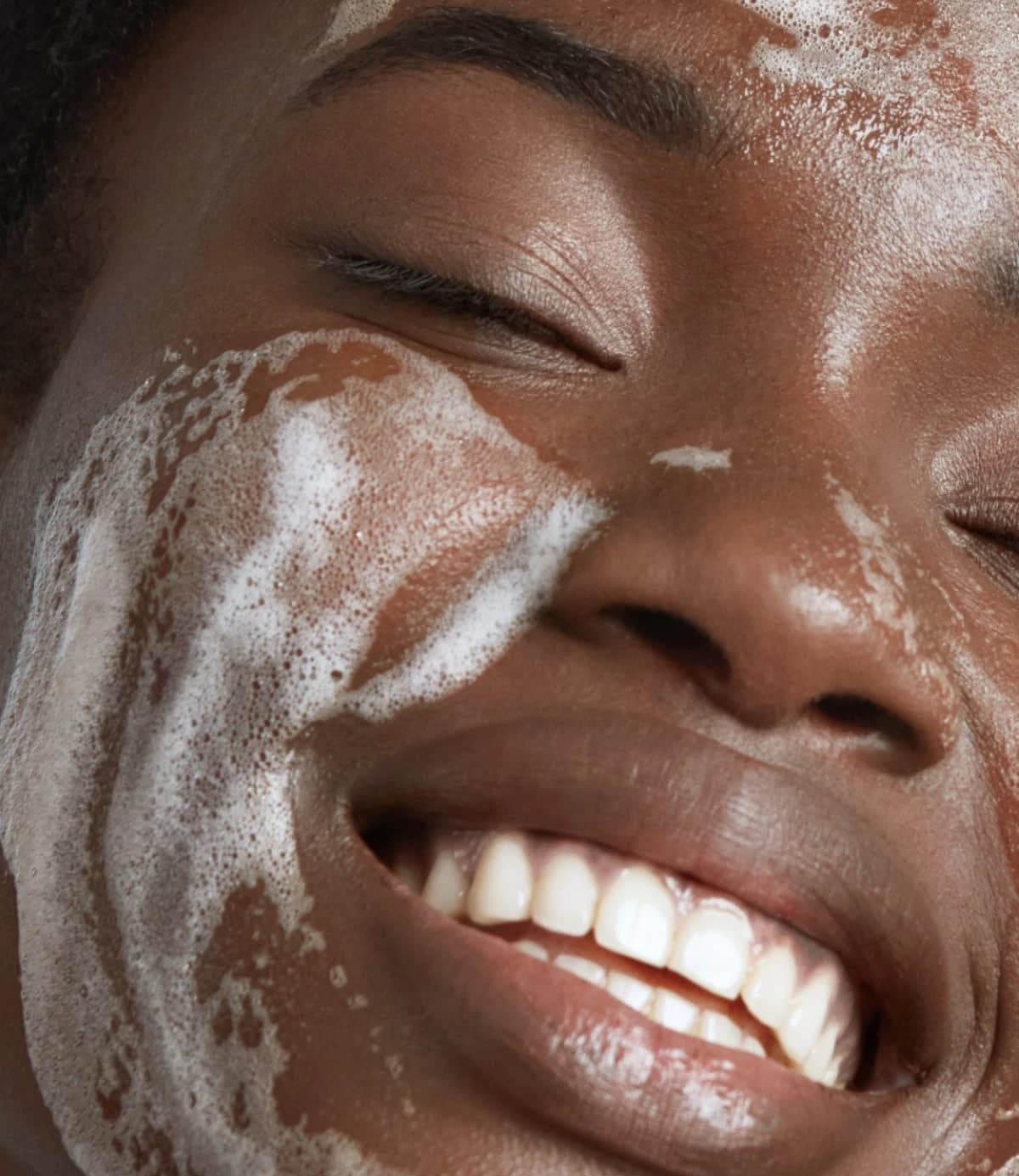 Femme souriante, le visage couvert de mousse nettoyante