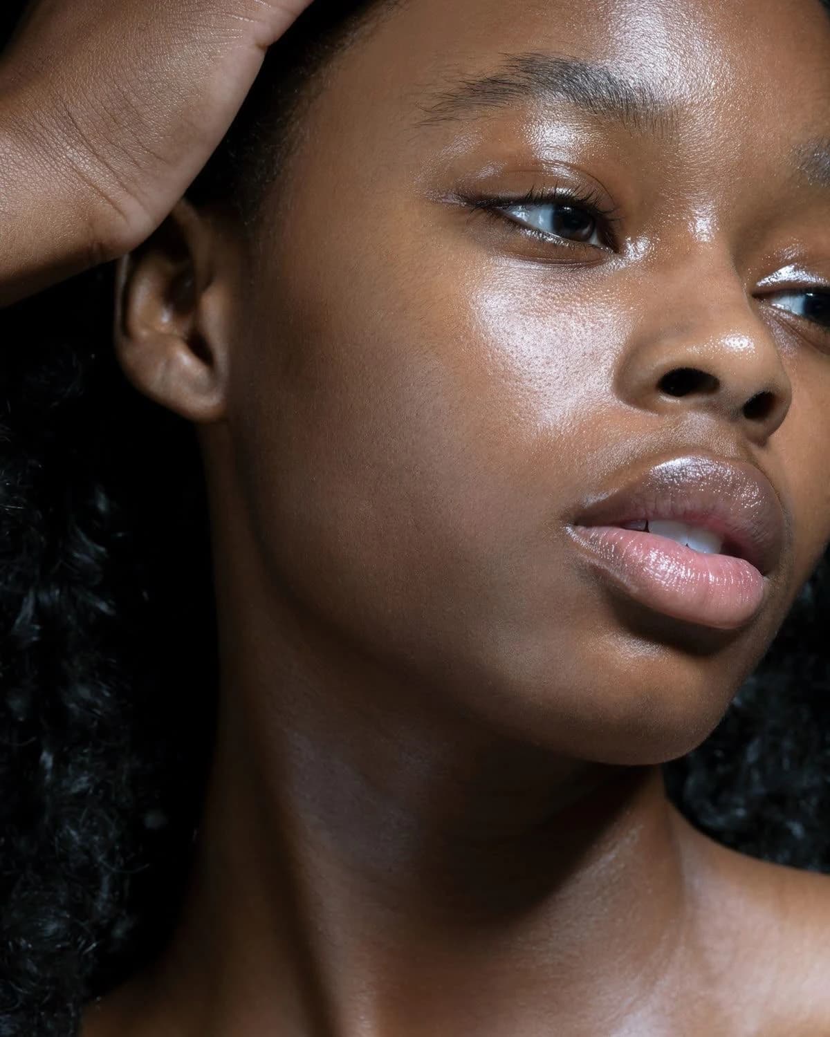 Femme, main dans les cheveux, peau lumineuse, regard de côté