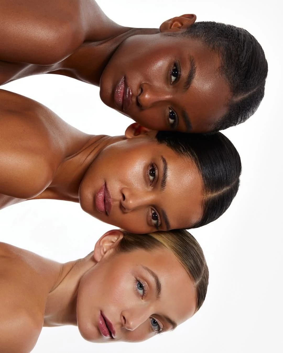 Trois femmes allongées, têtes rapprochées, peaux lumineuses